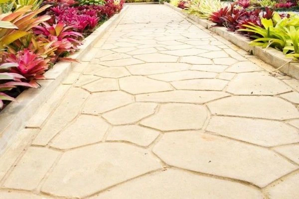 Camino de jardín con hormigón impreso en crema con plantas tropicales en Vitoria-Gasteiz
