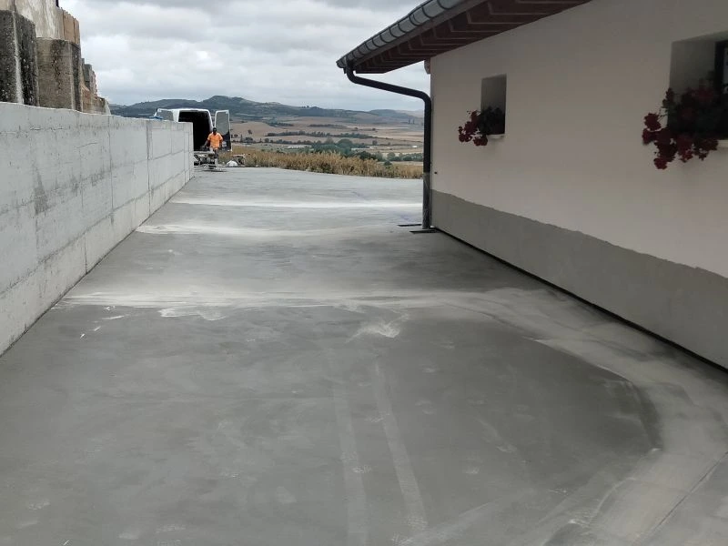 Entrada unifamiliar con hormigón impreso de doble tono: adoquín gris y marrón terracota